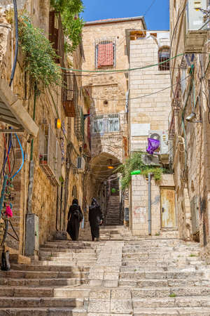 JERUSALEM, ISRAEL - JUNE 19, 2015: Two women in black clothes climb up the staircase street of the old town.のeditorial素材