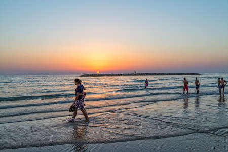 TEL AVIV, ISRAEL - JUNE 18, 2015: People enjoying the sea at sunset, riviera long promenade along skyline shot from the marine.のeditorial素材