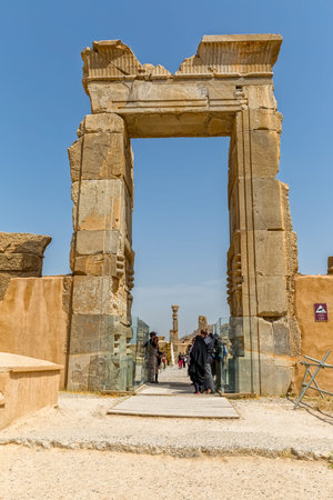 PERSEPOLIS, IRAN - MAY 3, 2015: People walking by the ruins of old giant gate, a capital of the...