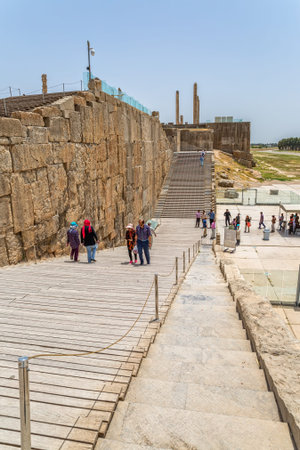 PERSEPOLIS, IRAN - MAY 3, 2015: Visitors walking the stairs at the entrance to the ruins of old city...