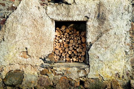 logs/wood stacked behind a window in a barn.の写真素材