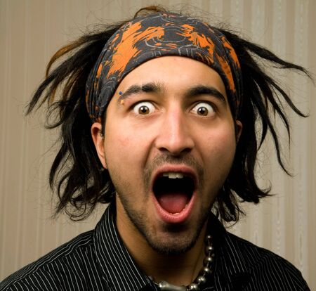 young male looks shocked with head band and stripped shirtの写真素材