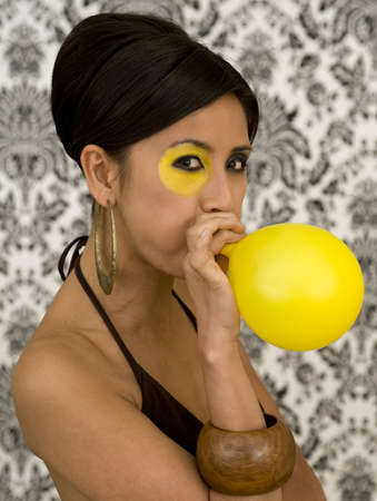 Beautiful asian model with funky make-up blow balloonの写真素材