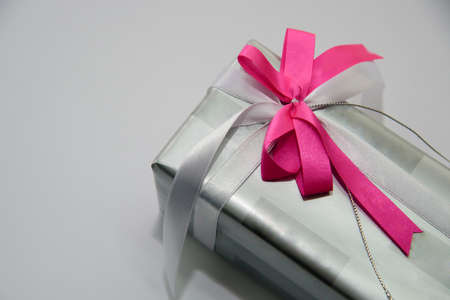 A gift box with a pink ribbon on a white backgroundの写真素材