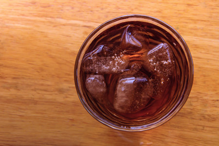 A glass of cola drink on a wooden floor