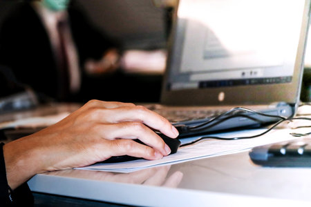 Close-up of female hands using laptop at desk in office.の写真素材