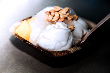 Scoops of ice cream in a wooden bowl with pine nutsの写真素材