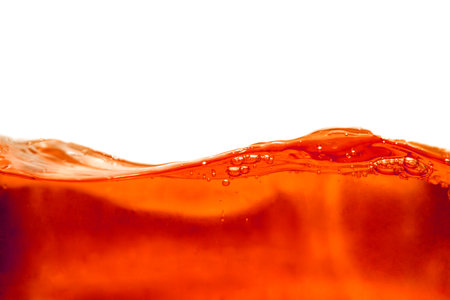 Orange water wave with bubbles isolated on white background. Close up.の写真素材
