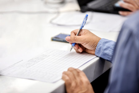 Close-up of businesswoman writing in notebook at desk in office