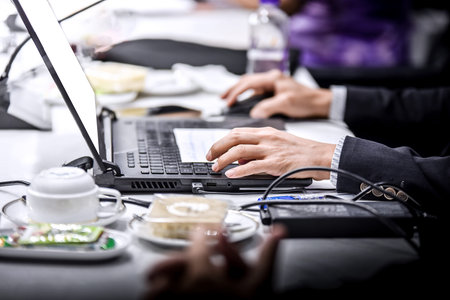 Close up of business people hands typing on laptop keyboard in office.