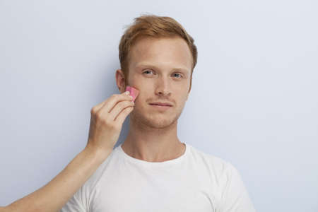Portrait of young man being served with facial cosmetic treatment の写真素材