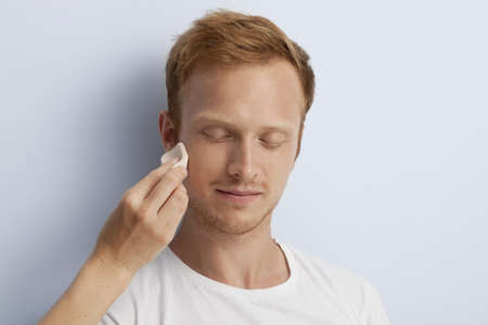 Portrait of young man being served with facial cosmetic treatment の写真素材