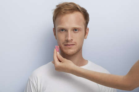 Portrait of young man being served with facial cosmetic treatment の写真素材