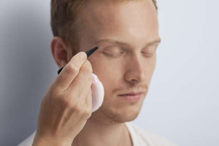 Portrait of young man being served with facial cosmetic treatment の写真素材