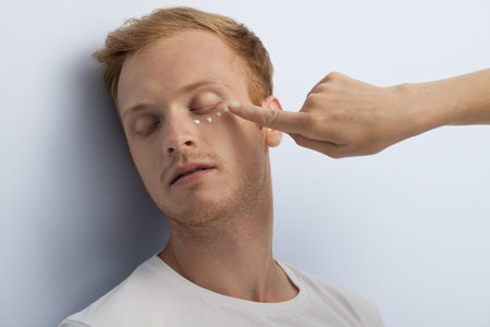 Portrait of young man being served with facial cosmetic treatment 