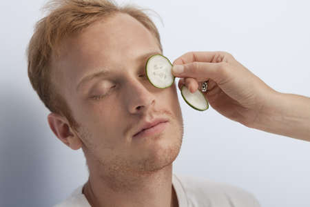 Portrait of young man being served with facial cosmetic treatment の写真素材