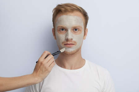 Portrait of young man being served with facial cosmetic treatment の写真素材