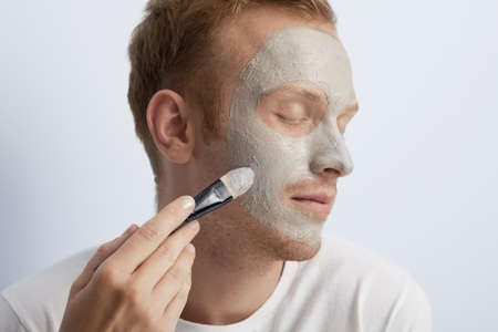 Portrait of young man being served with facial cosmetic treatment の写真素材