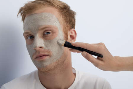 Portrait of young man being served with facial cosmetic treatment の写真素材