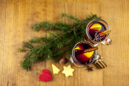 Two cubs of mulled wine with a branch of pine cakes and redd wooden heartの写真素材