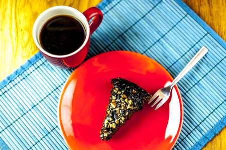 chockolate cake at the red plate with cup of coffe and silver forkの写真素材