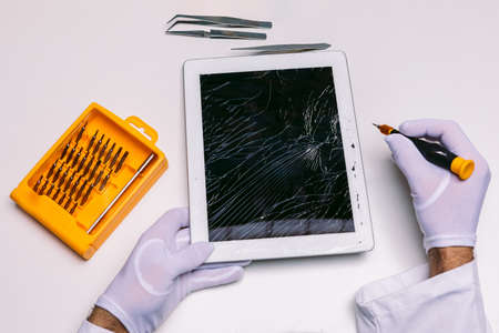 Hands of a gloved technician repairing a tablet with a broken glass. Technology maintenance conceptの写真素材