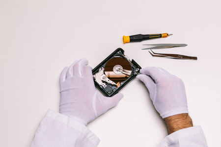 Hands of a technician with gloves repairing a hard drive. Technology maintenance concept
