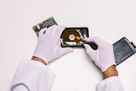 Hands of a technician with gloves repairing a hard drive. Technology maintenance concept