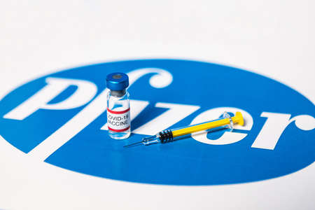 MADRID, SPAIN - JAN, 25, 2021: Vial with Covid-19 vaccine and syringe over Pfizer logoのeditorial素材