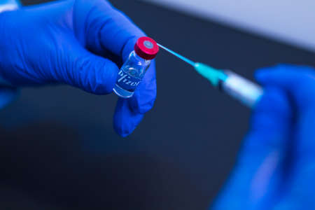 MADRID, SPAIN - JAN, 25, 2021: Vial with the vaccine for COVID-19 Pfizer company held by the hand of a doctor and in the other hand a syringe. Coronavirus vaccination conceptのeditorial素材