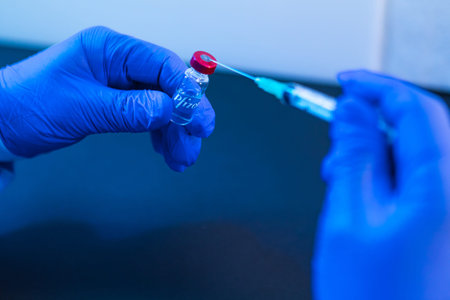 MADRID, SPAIN - JAN, 25, 2021: Vial with the vaccine for COVID-19 Pfizer company held by the hand of a doctor and in the other hand a syringe. Coronavirus vaccination conceptのeditorial素材