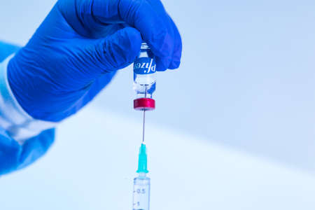 MADRID, SPAIN - JAN, 25, 2021: Doctor inserts the needle of a syringe into the vial with the COVID-19 vaccine Pfizer company to extract the liquid to vaccinate. Coronavirus vaccination conceptのeditorial素材
