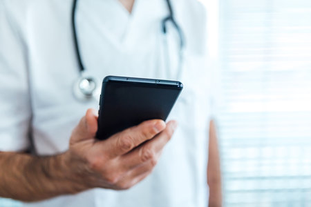 Mature male doctor - nurse wearing face mask, talking on mobile phone and holding a report next to a hospital medicine conceptの写真素材