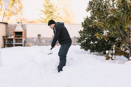 Man removing snow from the garden of his house with a shovel