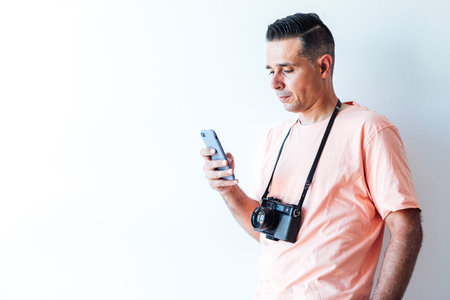 Man in pink t-shirt with an old-fashioned photo machine slung over his shoulder, looking at his...
