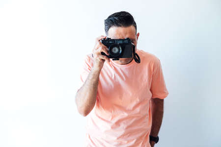 Man wearing a pink t-shirt, taking a picture with an old photo machineの写真素材