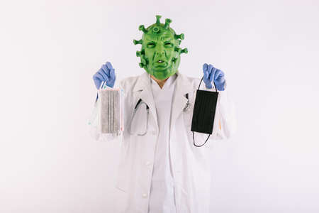 Person disguised as  virus with latex mask -   virus, wearing doctor's suit, holding large syringe, on white background.の写真素材