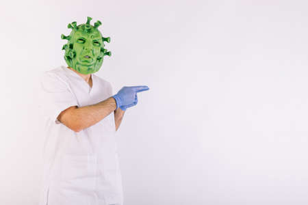 Person disguised as  virus with latex mask -   virus, wearing doctor's suit, holding large syringe, on white background.の写真素材