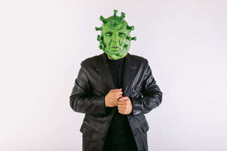 Person disguised as  virus with latex mask -   virus, wearing doctor's suit, holding large syringe, on white background.の写真素材