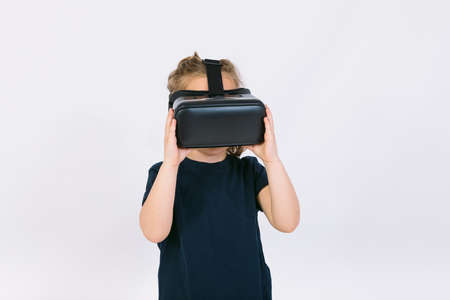 Little girl wearing virtual reality glasses with hands hold goggles on white backgroundの写真素材