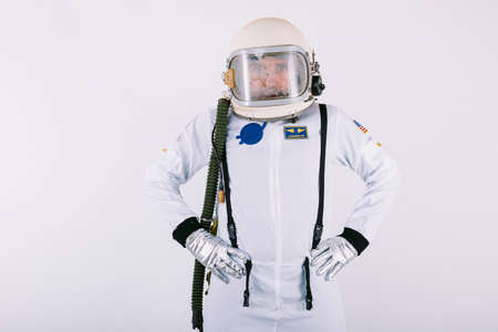 Male cosmonaut in space suit and helmet, hands on waist, on white background.の写真素材