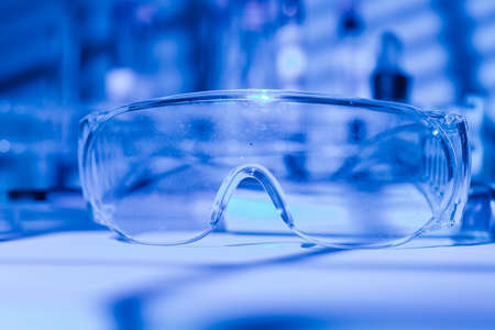 Protective glasses of scientist researcher on a laboratory table, with blue light environmentの写真素材