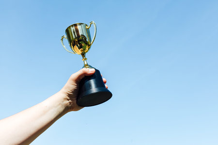 Hand raise a champion's glass, with the sky in the background. Victory concept
