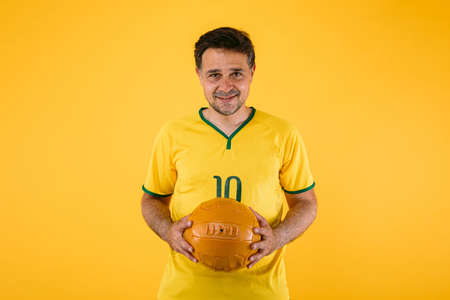 Soccer fan wearing a white t-shirt with black, red and yellow stripes, poses with crossed armsの写真素材