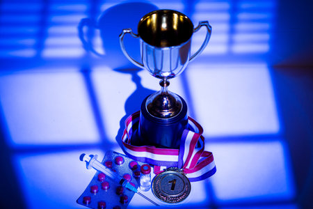 Gold medal and champion's cup, syringe with doping substance, pill tablet and vial with prohibited...