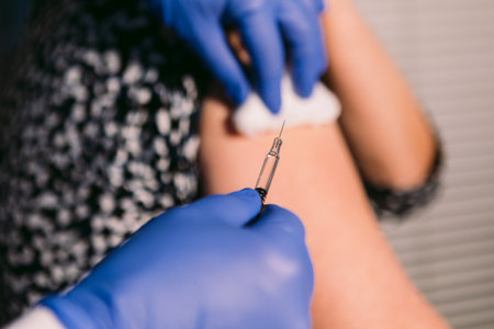 Nurse disinfects an older woman's arm with cotton to inject a vaccineの写真素材