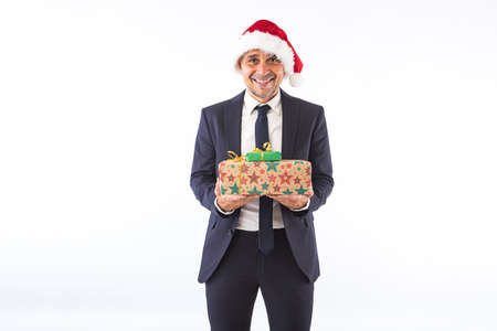 Businessman dressed in suit, tie and Christmas hat of Santa Claus, smiling, on white background. Christmas celebration concept.の写真素材