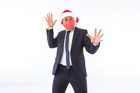 Businessman dressed in suit, tie and Christmas hat of Santa Claus, smiling, on white background. Christmas celebration concept.の写真素材