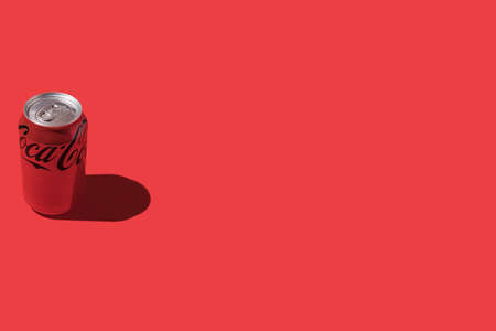 Madrid, Spain - November 26, 2021: Coca cola can with hard shadow, on the left side, on red background.のeditorial素材