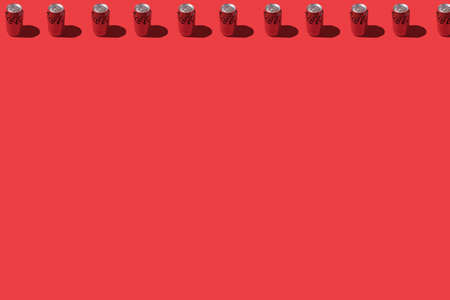 Madrid, Spain - November 26, 2021: Coca cola cans pattern with hard shadow, on top line, on red background.のeditorial素材